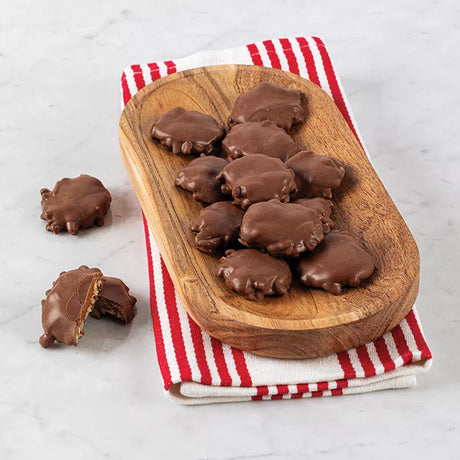 A wooden board with bear claw bites with pecans on a red and white striped napkin.