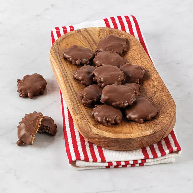 A wooden board with bear claw bites with pecans on a red and white striped napkin.