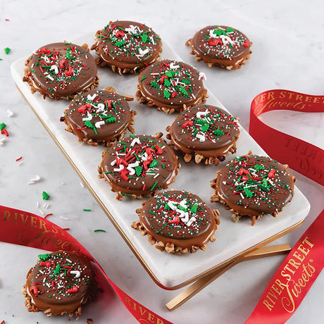 A tray of festive sprinkle topped milk chocolate bear claws with red and green holiday sprinkles, presented with a red ribbon.